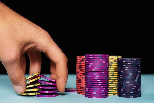 A hand performing a chip trick with stacks of poker chips adjacent.