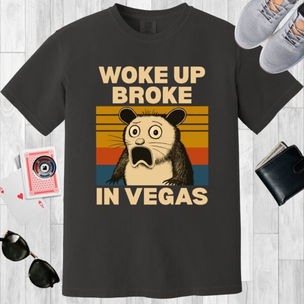 Graphite colored unisex crewneck poker-themed T-shirt. Design features the text 'Woke up broke in Vegas'. Image of a stunned possum on a sunset background.